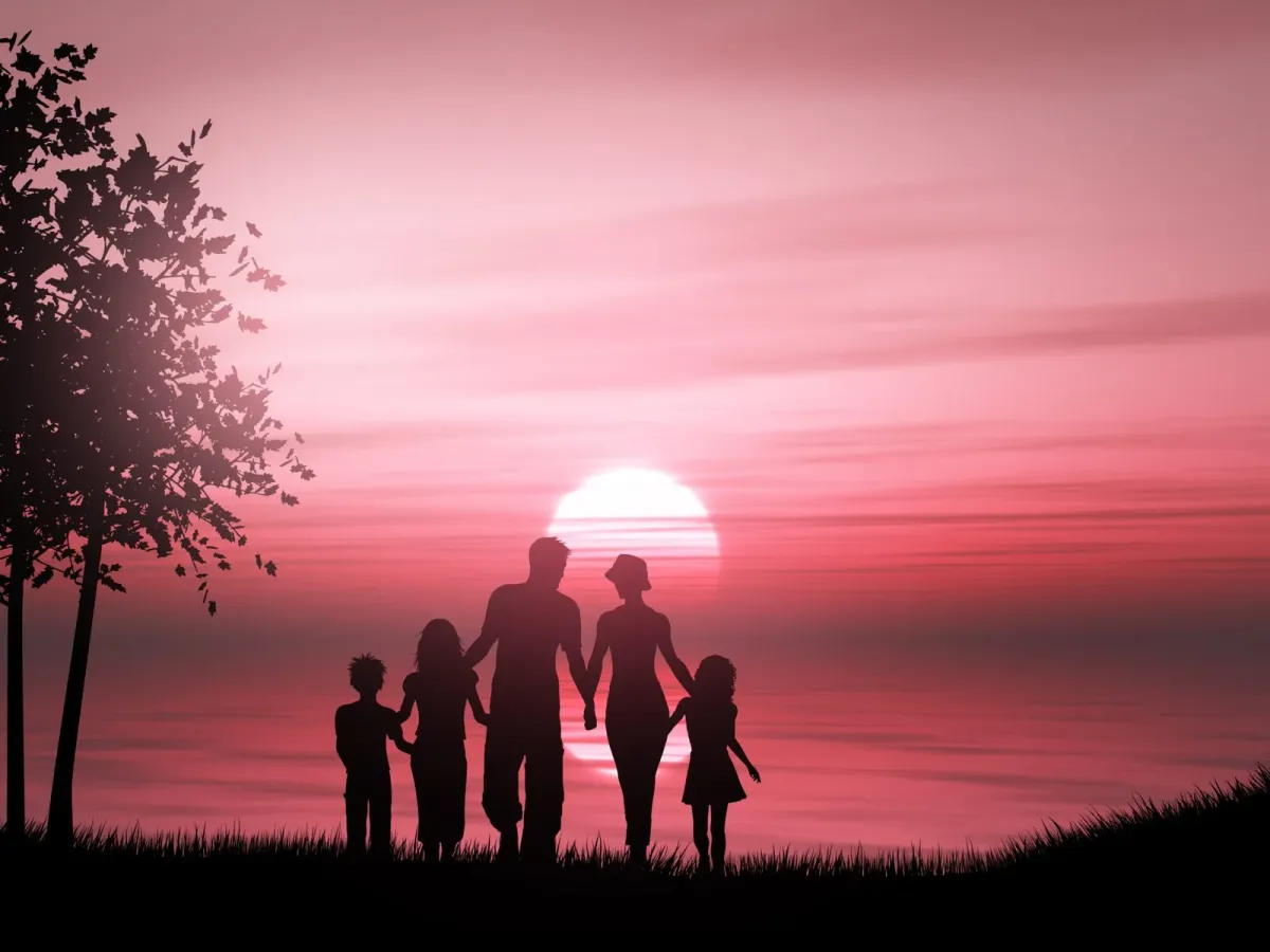 Silhouette di una famiglia di cinque persone che si tengono per mano in riva al mare al tramonto