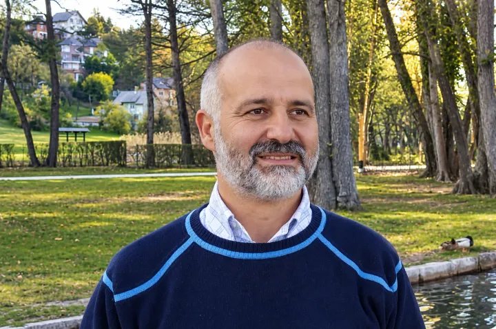 Iuri Silvestri sorride in un parco sul lago, con gli alberi alle spalle
